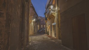 A narrow street with buildings on either side, a cobblestone road, and a few parked cars. - Maria Rosa Suites (Victoria)