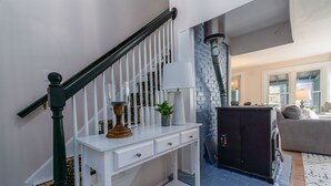 Un escalier avec une console blanche, un meuble noir et un mur en briques bleues.