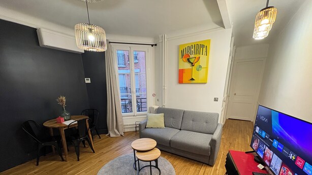 Ein modernes Wohnzimmer mit einem grauen Sofa, einem runden Couchtisch und einem roten TV-Schrank.