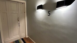 Ein Korridor mit grauer Wand, Holzboden, weißer Tür und einem Schild mit der Nummer 5.