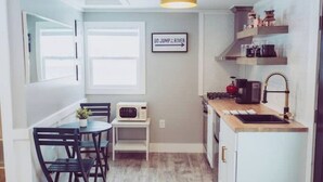 Une cuisine compacte comprenant un coin repas, un four à micro-ondes, un évier et un panneau affiché sur le mur.
