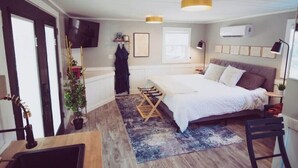 Une chambre à coucher avec un lit, des tables de chevet, une télévision et une fenêtre.