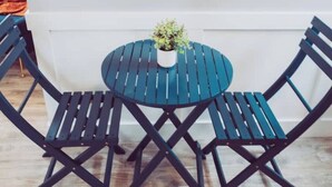Une table ronde ornée d’un pot de fleurs au centre, entourée de deux chaises au design simple et moderne.
