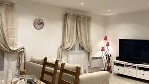 Una sala moderna con comedor, que incluye un sofá, televisión y una mesa de comedor dispuesta con platos y vasos.