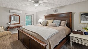 Une chambre à coucher avec un lit en bois, un ventilateur de plafond, un miroir, une table de chevet et une commode.