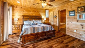 A wooden cabin bedroom with a bed, nightstands, a ceiling fan, and a wooden floor. - Summer Starts Here + Breathtaking Views (Pigeon Forge)