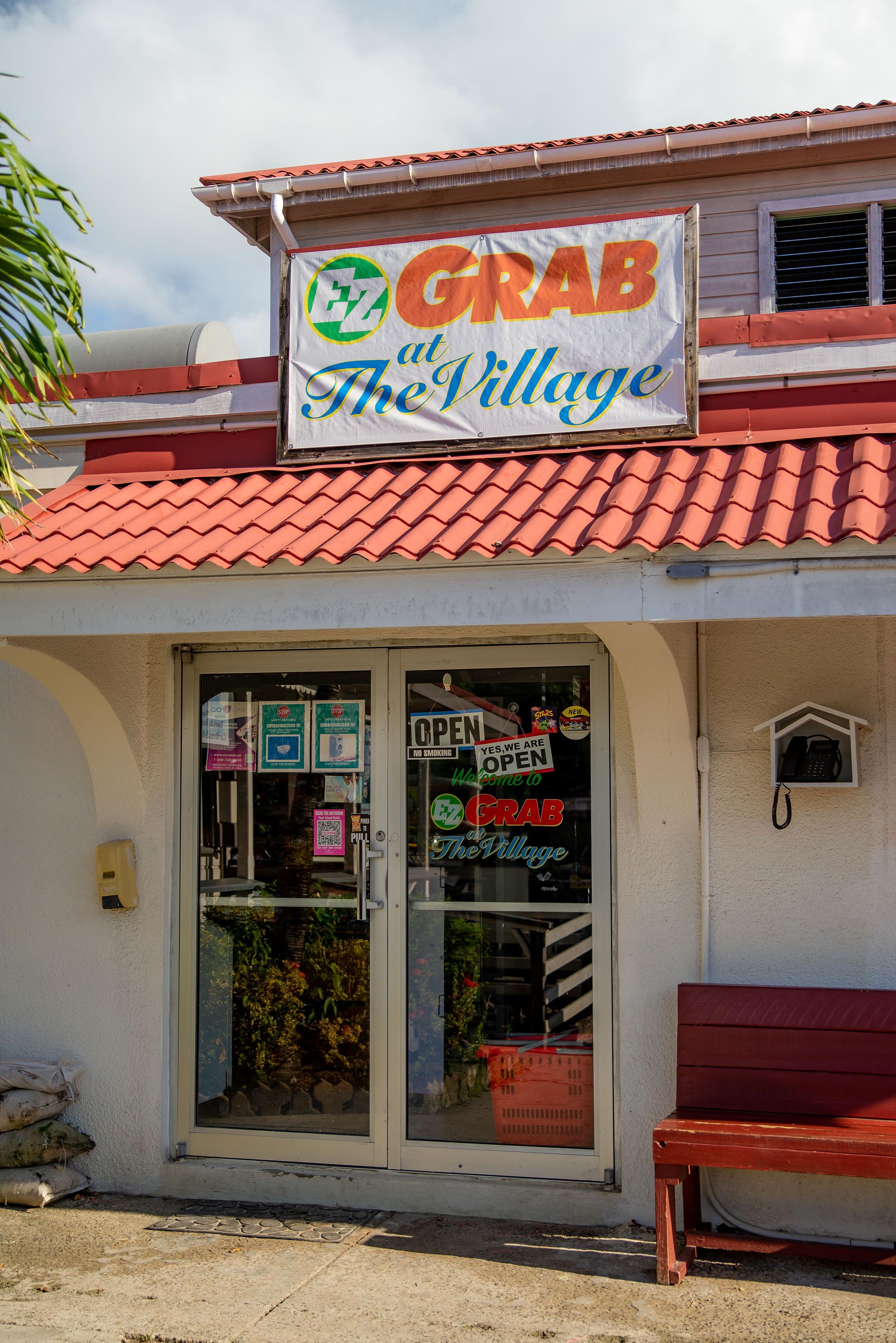 Une devanture de magasin avec une enseigne indiquant « EZ CRAB at The Village » et un banc rouge à l’extérieur.