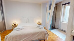 A bedroom with a bed, two bedside tables with lamps, a window, and a wooden floor. - Roesselmann 2bdrm 1 Parking (Colmar)