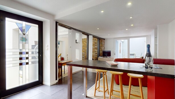 A modern kitchen with a central island, bar stools, and a dining area with a red sofa. - Roesselmann 2bdrm 1 Parking (Colmar)
