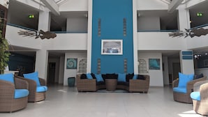 A spacious lobby with a central blue wall, multiple levels, and wicker furniture with blue cushions. - Large Pool/ 1 BR/1Bath  Apt. in Beautiful St. Martin in Simpson Bay! (Simpson Bay)