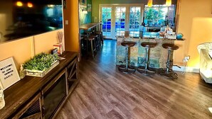 A modern kitchen with a bar area, wooden flooring, and a sign reading "Hello Spring". - VEGAS Garden Oasis (Las Vegas)