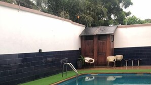 A rectangular swimming pool with a metal ladder, surrounded by artificial grass. - Whyte View Lodge (Sekondi-Takoradi)