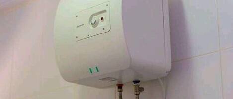 Calentador de agua blanco instalado en una pared con azulejos y una franja azul.