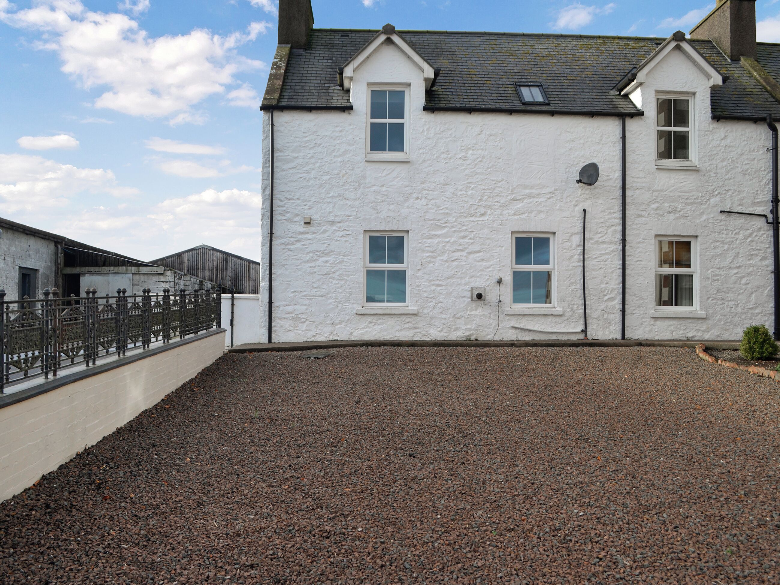A white building with multiple windows and a gravel driveway.