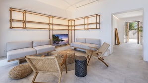 A modern living room with a sectional sofa, two armchairs, a coffee table, and a wall-mounted TV. - VILLA ES BARCARES (Alcúdia)