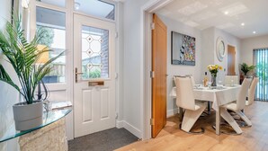 Un coin repas avec une table dressée pour quatre personnes, une plante en pot et une vue sur l’extérieur.