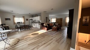 Amplia sala de estar con una mesa de comedor, un sofá y una cocina al fondo.
