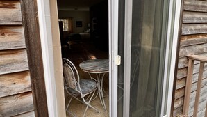 Una casa de madera con un cerramiento de vidrio corredizo que da a un patio con mesa y sillas.