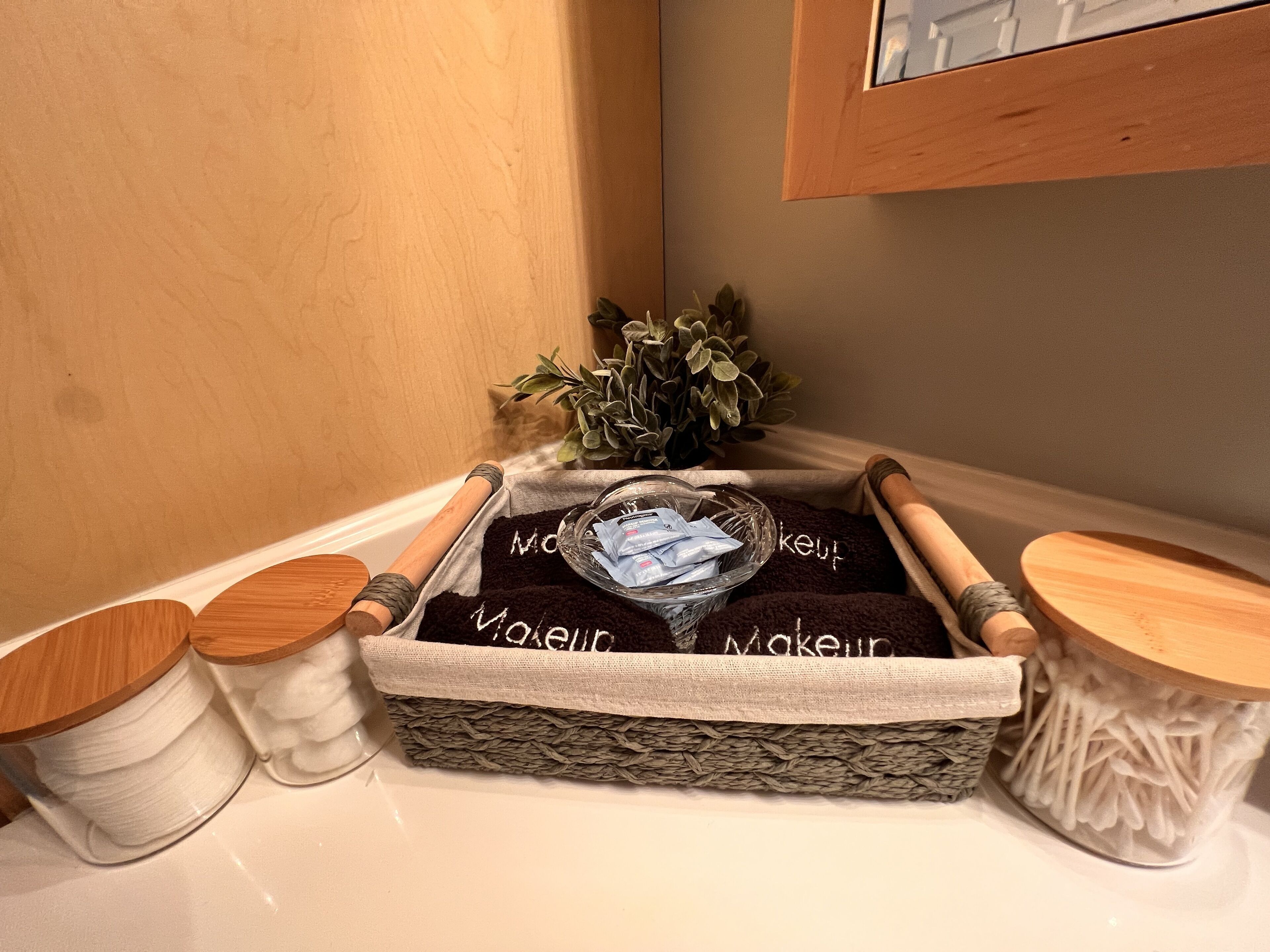 Un coin d’une pièce avec un panier en osier contenant une boîte de mouchoirs et une petite plante.