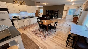 Una cocina moderna con armarios blancos, una mesa de comedor de madera y una isla de cocina.