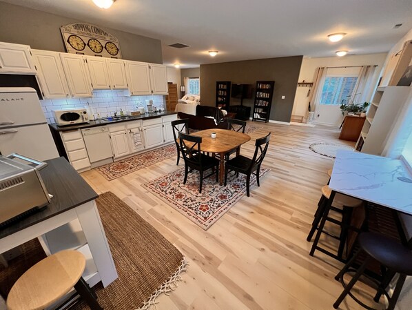 A modern kitchen with white cabinets, a wooden dining table, and a kitchen island.