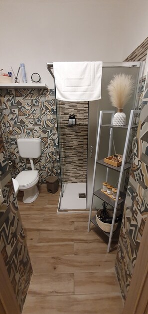 A compact bathroom with a toilet, shower, and shelves with toiletries. - Apartment in the center of Palermo (Palermo)