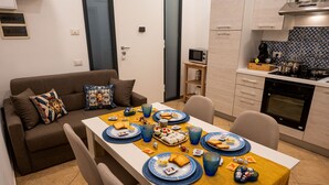 A modern kitchen with a dining table set for a meal, a sofa with decorative pillows, and a microwave. - Apartment in the center of Palermo (Palermo)
