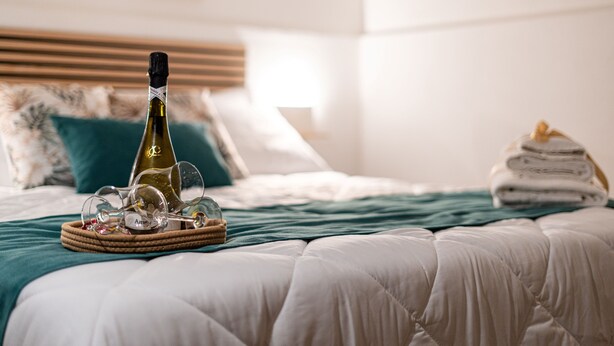 A neatly made bed with a bottle of champagne, glasses, and a woven tray on the bed. - Apartment in the center of Palermo (Palermo)