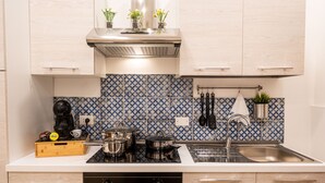 A modern kitchen with light wood cabinets, a stainless steel sink, and a patterned backsplash. - Apartment in the center of Palermo (Palermo)