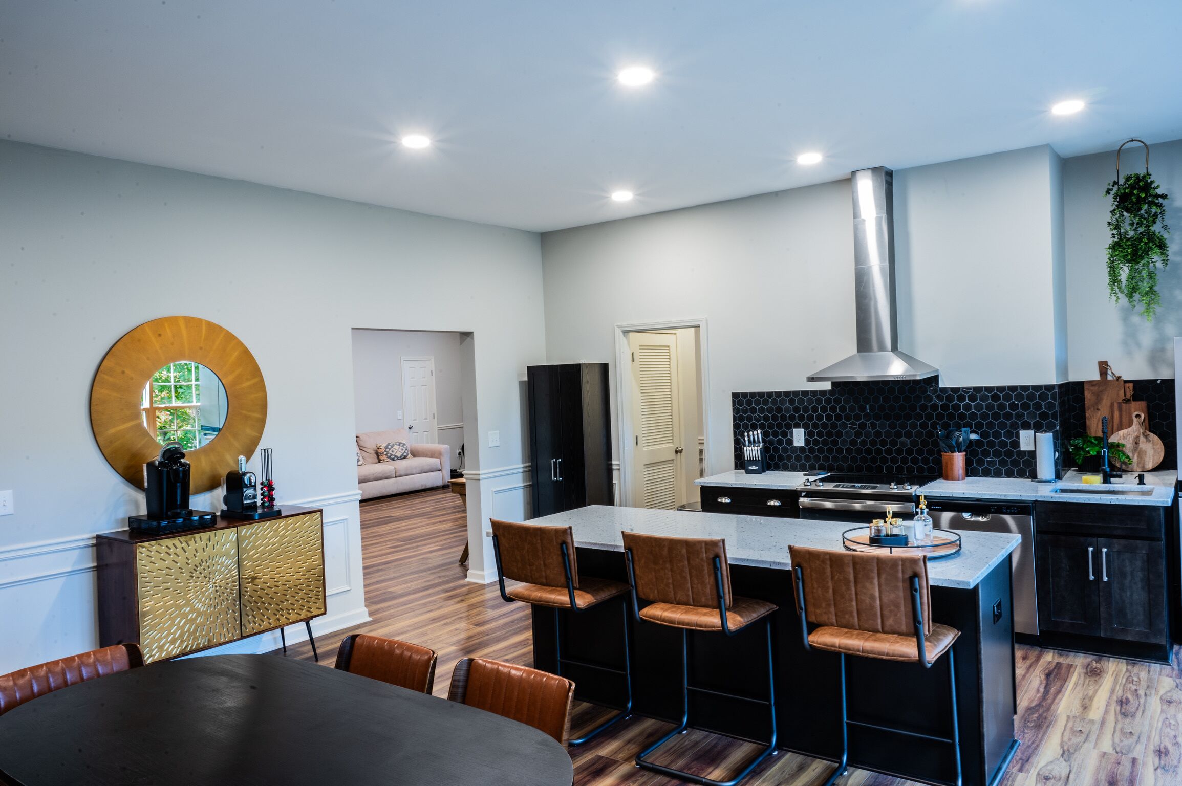 Una cocina moderna con una isla central, taburetes de bar y un comedor con mesa y sillas.