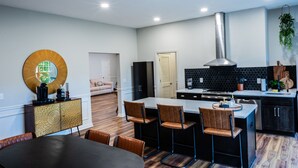 A modern kitchen with a central island, bar stools, and a dining area with a table and chairs. - Mid-Century Modern gem in the heart of the country, close to Lake Lanier.  (Auburn)