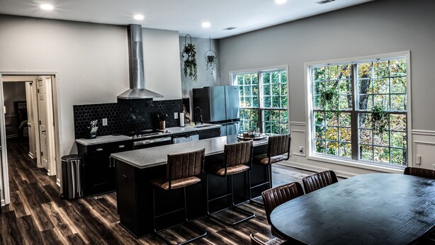 A modern kitchen with a central island, bar stools, and a dining table. - Mid-Century Modern gem in the heart of the country, close to Lake Lanier.  (Auburn)