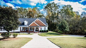 A two-story house with a front porch, a driveway, and a well-maintained lawn. - Mid-Century Modern gem in the heart of the country, close to Lake Lanier.  (Auburn)