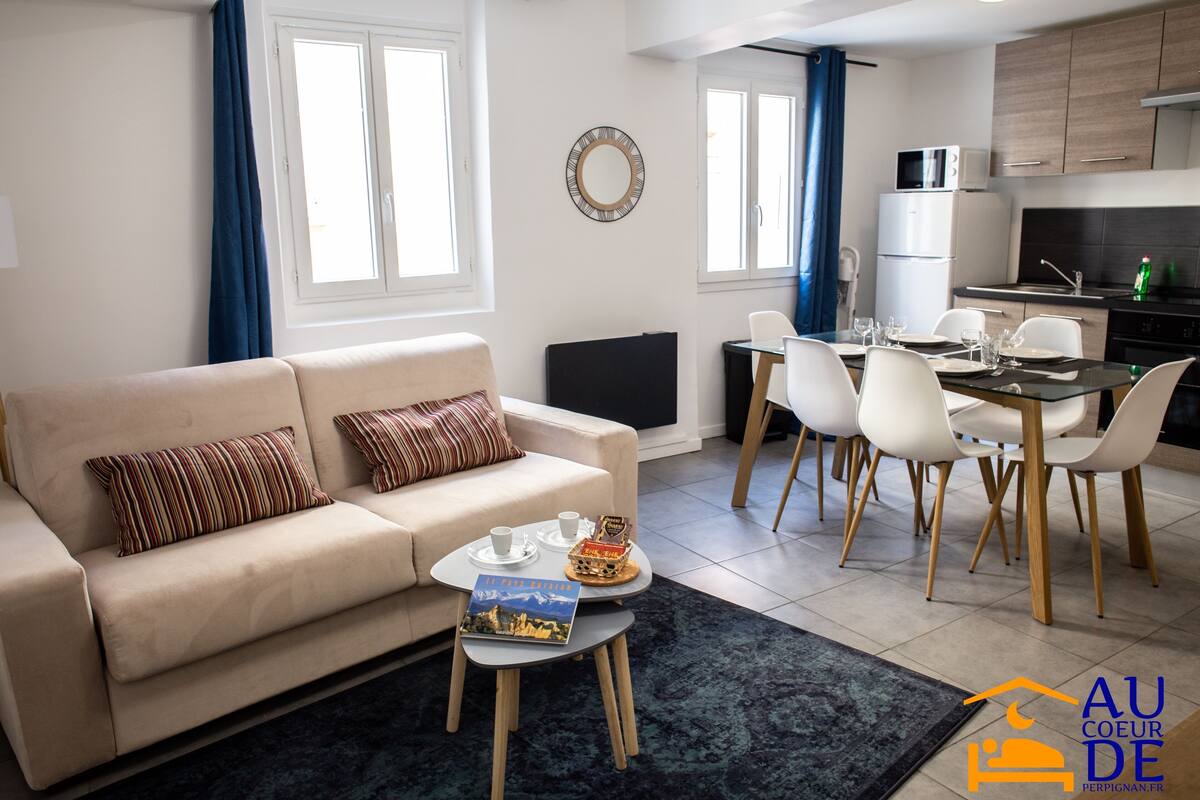 A modern living room with a sofa, coffee table, and dining area with chairs and a table.