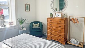 A bedroom with a bed, dresser, chair, mirror, and a window with a view. - Muirston Farmhouse - UK44977 (Cumnock)