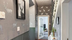 A hallway with patterned wallpaper, a framed deer picture, a radiator, and a door leading to another room. - Muirston Farmhouse - UK44977 (Cumnock)