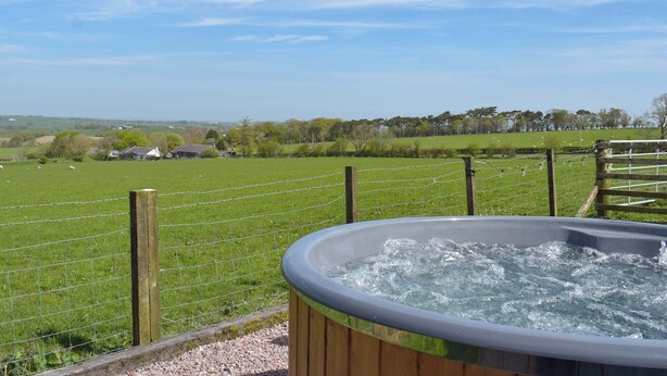 A hot tub with a wooden frame, surrounded by a grassy field and a wooden fence. - Muirston Farmhouse - UK44977 (Cumnock)