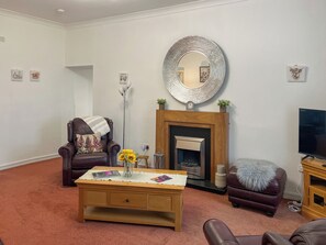 A living room with a fireplace, a sofa, a coffee table, and a television.