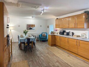 Una cocina moderna con armarios de madera, una mesa de comedor preparada para cuatro personas y un sillón azul.