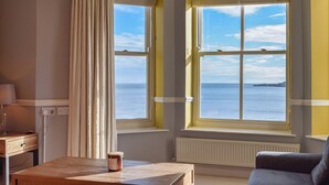 Ein Zimmer mit Meerblick, einem Holztisch, einer Couch und einer Lampe.