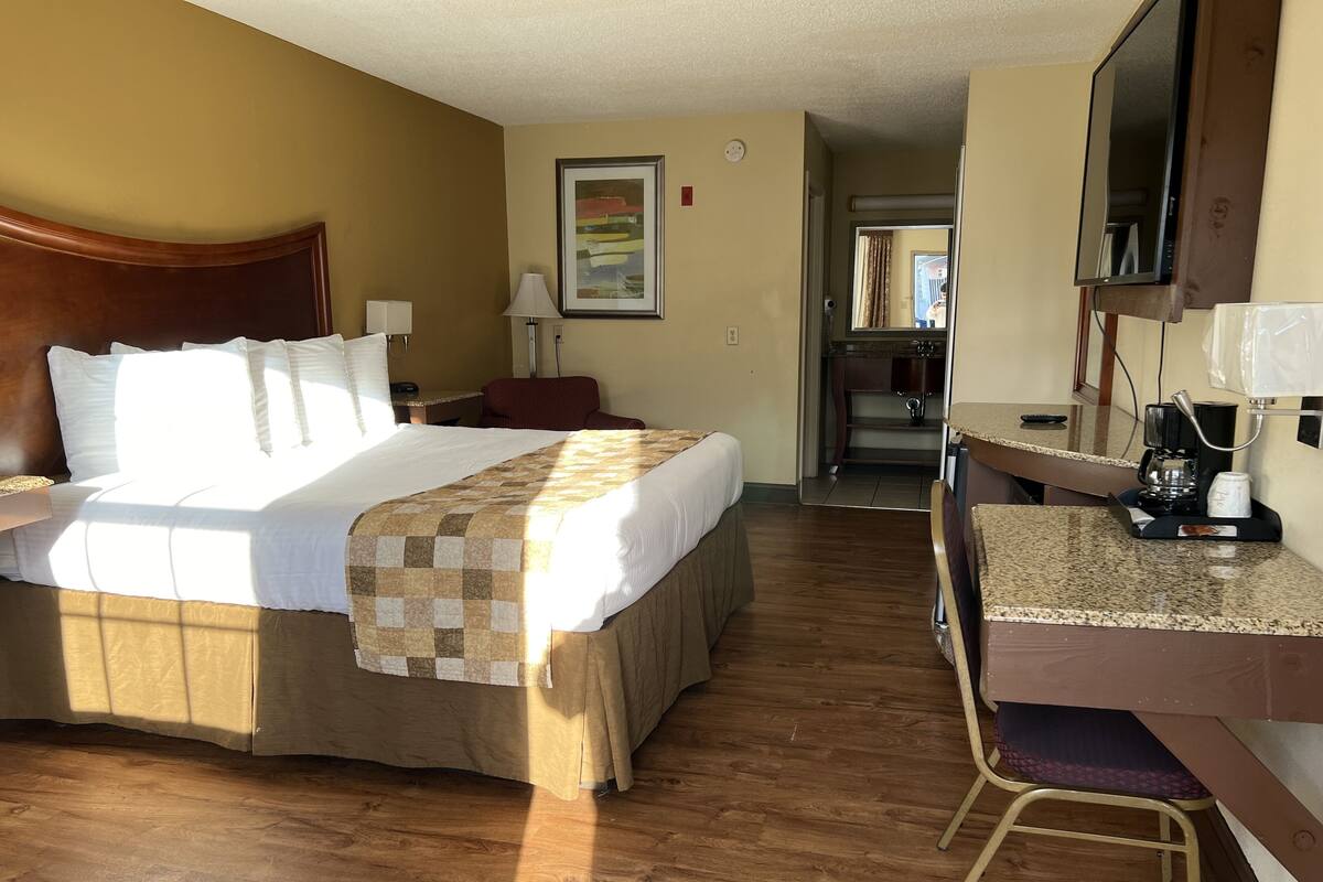 A hotel room with a large bed, a desk with a chair, a microwave, and a coffee maker.