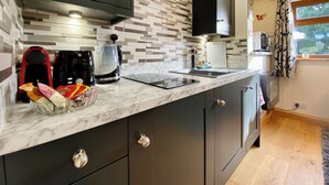 Una cocina moderna con armarios oscuros, encimera de mármol y salpicadero decorado.