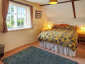 A bedroom with a bed, a window with curtains, a bedside lamp, a framed picture on the wall, and a rug on the floor. - 2 bedroom accommodation in Chillaton, near Tavistock (Chillaton, near Tavistock)