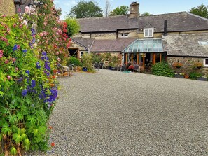 A building with a gravel driveway, outdoor seating, and a glass conservatory. - 2 bedroom accommodation in Chillaton, near Tavistock (Chillaton, near Tavistock)