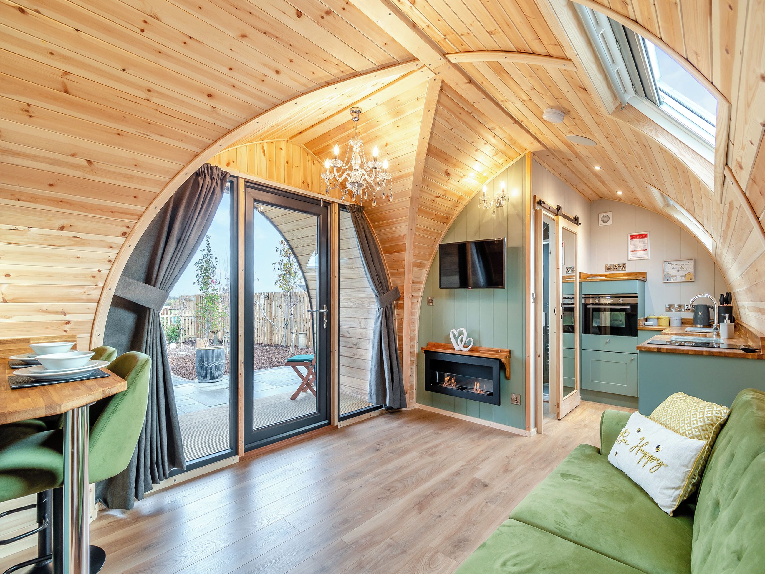 Un intérieur chaleureux, avec des éléments en bois, comprenant un coin repas, une cheminée et une cuisine.
