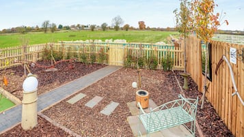 A garden with a wooden fence, a metal bench, and a pathway.