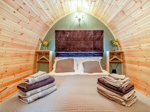 A cozy, wooden-paneled room with a bed, pillows, and towels. - 1 bedroom accommodation in Church Broughton, near Derby (Church Broughton, near Derby)