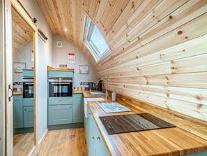 A compact kitchen with wooden walls, a built-in oven, and a small window. - 1 bedroom accommodation in Church Broughton, near Derby (Church Broughton, near Derby)