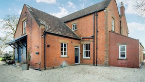 A red brick house with a sloped roof, a front door, and a small porch area. - 2 bedroom accommodation in Burtle, near Glastonbury (Burtle, near Glastonbury)