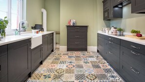 A kitchen with dark cabinets, a tiled floor, a window with a view, and a microwave above the cabinets. - 2 bedroom accommodation in Burtle, near Glastonbury (Burtle, near Glastonbury)